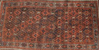 A Belouch tribal rug, the central panel set with repeating lozenge shaped medallions on a red, blue,