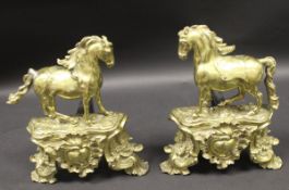 A pair of late 19th century brass chenets in the form of a horse upon a base in the Louis XV Rococo