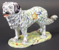 A late 19th/early 20th Century French faience figure of a stylised Pyrenean Mountain Dog with all