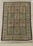 A silk rug, the central panel set with three rows of floral decorated panels, within a sky,