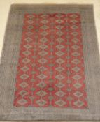 A Bokhara carpet , the central pattern set with repeating diamond shaped medallions on a red ground,