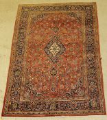 A Kashan rug, the central panel set with a floral decorated medallion on a red ground,