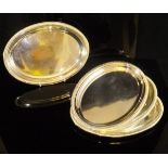 A set of four modern silver oval trays with reeded edges (by Barley Ellis Silver Company,