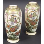 A pair of Japanese Satsuma vases with panels of figures in interior settings amongst trailing