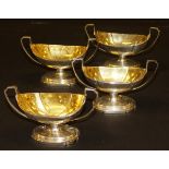 A set of four George III silver boat-shaped salts with twin handles and gilded interior,