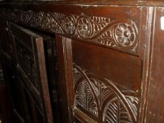 An 18th Century oak single door wardrobe with flower carved frieze above panelled door with leaf