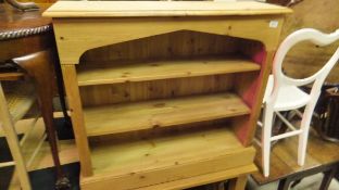 A pine low open bookcase with two adjustable shelves, raised on a plinth base,