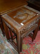 A Chinese hardwood nest of three tables, each with carved decoration depicting figures,