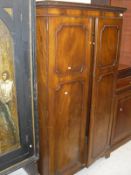 An Edwardian mahogany two door wardrobe, the moulded top with Greek key style design,