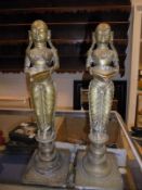 A pair of Indian brass oil lamp figures holding bowls, raised on turned circular plinths,