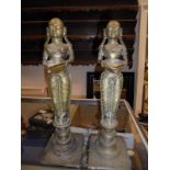 A pair of Indian brass oil lamp figures holding bowls, raised on turned circular plinths,