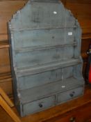 A petroleum blue painted wall hanging kitchen rack with various shelves above two drawers,