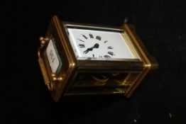 A brass carriage clock with Roman numerals to the enamelled dial,