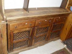 A Eastern hard wood dresser base with three drawers above three cupboard doors with latticed panels,