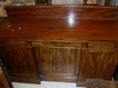 A 19th Century mahogany sideboard with raised back to plain top above central drawer and three