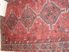 A Caucasian rug the central panel set with three joined diamond shaped medallions on a red ground