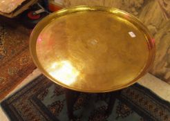 An Eastern coffee table with brass circular tray, raised on a hardwood folding base,