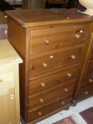 A pair of modern pine chests of drawers, the plain tops above five drawers with turned knob handles,
