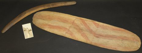 An aboriginal boomerang and an aboriginal wooden shield painted with red chevron and integral