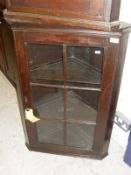 A late George III oak hanging corner cabinet with glazed and barred doors enclosing two shelves