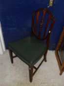 A set of four early 20th Century mahogany framed shield back dining chairs with green leather