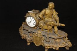 A French brass mantle clock in the form of a resting gentleman, his hat in hand,