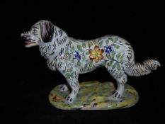 A late 19th/early 20th Century French faience figure of a stylised Pyrenean Mountain Dog with all