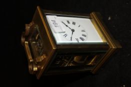 A brass and glass carriage clock with Roman numerals to the enamelled dial