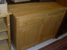 A modern oak sideboard, the plain top above two drawers and two cupboard doors,
