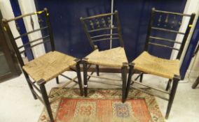 Three ebonised Sussex style chairs with rush seats (no arms)