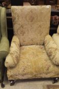 A Victorian upholstered armchair on turned front legs to brass castors