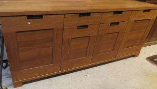 A modern teak sideboard with two drawers above two cupboard doors flanked by two further cupboard