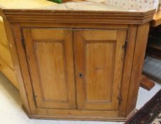 A pine wall-hanging corner cupboard of two doors enclosing two shelves