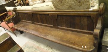 An oak church pew with panelled back and plank seat