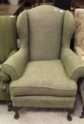 An early to mid 20th Century upholstered wing back scroll armchair on carved cabriole front legs to