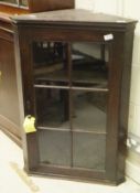 A late George III oak hanging corner cabinet with glazed and barred doors enclosing two shelves