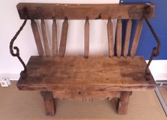 A rustic oak bench made from various parts with iron hand and arm rests