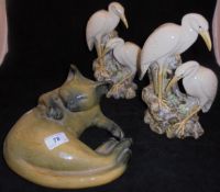 A pair of glazed pottery stork vases and a green glazed pottery figure of a recumbent cat