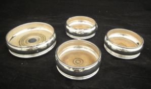 Three modern silver wine coasters and another similar larger coaster