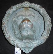 A modern verdigris bronze door knocker of lion mask and wreath form