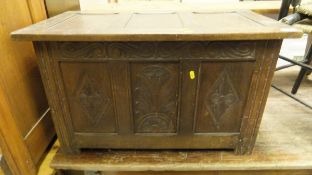 A 20th Century oak coffer with three carved panels to the front on style supports