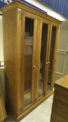 A modern pitch pine three door bookcase cabinet on plinth base