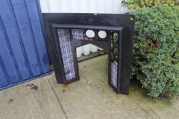 A cast iron fire surround with various blue and white inset tiles