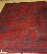 A Turkish rug, the central panel set with stylised floral and geometric design on a red ground,