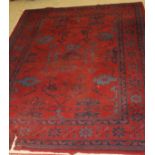 A Turkish rug, the central panel set with stylised floral and geometric design on a red ground,