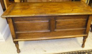 An oak blanket box, the plain top above a square tapered base with panelled sides,