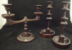 A pair of turned mahogany candlesticks on circular drip tray bases,
