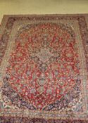 A Persian rug, the central panel set with floral decorated medallion on a red ground,