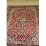 A Persian rug, the central panel set with floral decorated medallion on a red ground,