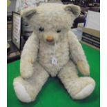 A pale pink plush bear with shallow hump back and amber / black eyes